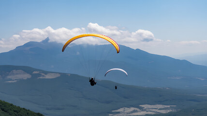 Paragliders Soaring Over a Mountainous Landscape Under a Cloudy Sky paragliding flying