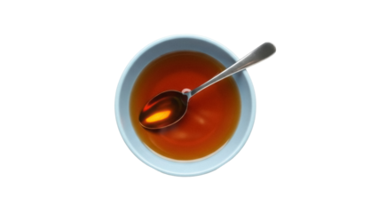 Isolated bowl of dark amber liquid, spoon resting inside, overhead view, sweet syrup, healthy diet