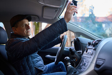 Man adjusting rearview mirror in car
