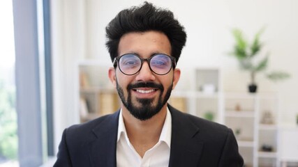 This portrait features a smiling Indian businessman wearing glasses and a suit, exuding confidence and professionalism