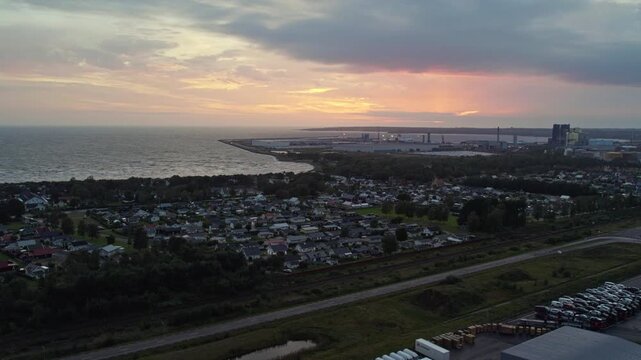 Warm golden hour aerial over &Ouml;stra Stranden, Halmstad&rsquo;s iconic long sandy beach with shallow turquoise water and adjacent modern residential neighbourhood.