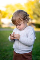 Portrait of happy little boy playing by himself in the park. Colorful fall outdoors