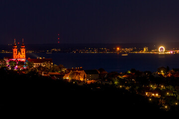 Illuminated church at night by the lake, view of Lake Balaton from the Tihany lookout in Hungary.