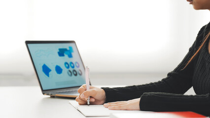 デスクでノートパソコンを見ながら勉強する女性