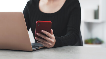 A woman working on a laptop and smartphone