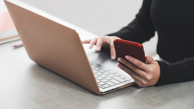 A woman working on a laptop and smartphone