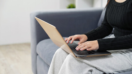 部屋でノートパソコンを使う女性