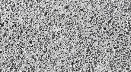 Close-up grayscale capture of porous concrete with rugged texture and natural cavities. Ideal for industrial themes, construction visuals, design overlays, or gritty background applications.