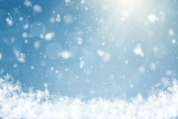 Winter background with bright sunlight, soft falling snow, bokeh light effects, and frosty white snowflakes along the bottom against a clear blue sky