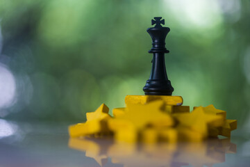 Obraz premium King chess piece remaining upright on a pile of yellow stars, representing business strategy and competition, symbolizing triumph, strategy, and overcoming challenges