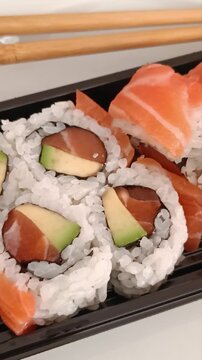Makis au saumon et avocat avec sushi sur plateau noir et baguettes japonaises