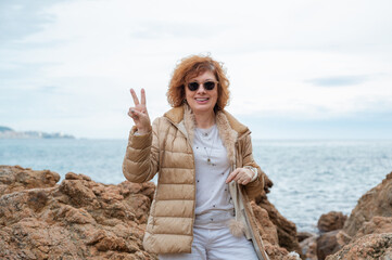 Redhead woman smiling showing peace sign on beach