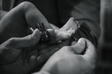 Baby feet. Black and white photo. Priest and godfather stretch hands to legs. Temple, Orthodox. Unction at baptism. Close Up of tiny baby feet, the sacrament of baptism ceremony. Anointing.
