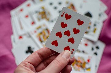 A deck of playing cards is scattered on the pink background.