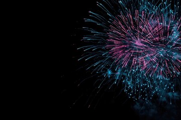 Fototapeta premium Colorful fireworks burst against a stark black sky, displaying vibrant pink and teal hues