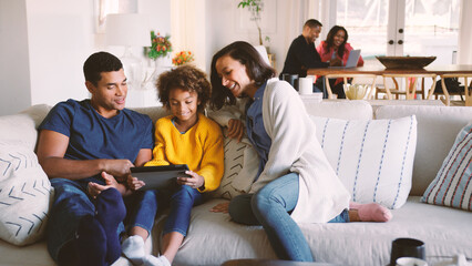 Multi Generation Family At Home With Parents And Daughter Using Digital Tablet In Foreground