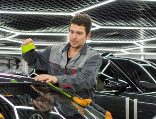 Automobile special workers replacing windscreen or windshield of a car in auto service station...