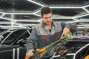 Automobile special workers replacing windscreen or windshield of a car in auto service station garage. Glass of the car, removed with the help of professional suction cups. The process of car repair. 