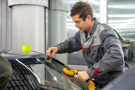 Automobile special workers replacing windscreen or windshield of a car in auto service station garage. Glass of the car, removed with the help of professional suction cups. The process of car repair. 