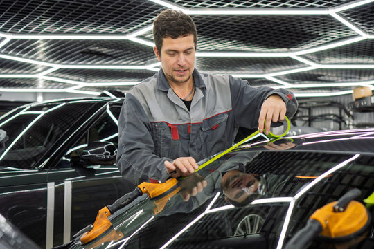Automobile special workers replacing windscreen or windshield of a car in auto service station garage. Glass of the car, removed with the help of professional suction cups. The process of car repair. 