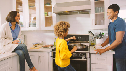 Daughter Preparing Meal in Kitchen Watched By Parents