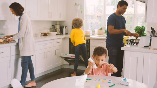 Family At Home In Kitchen Cooking, Doing Chores And Painting Picture