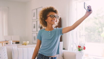 Girl Wearing Glasses Posing For Selfie On Mobile Phone In Lounge At Home