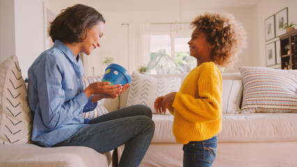 Daughter Giving Mother Plant Pot That She Has Decorated Herself Sitting On Sofa At Home