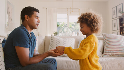 Daughter Giving Father Clay Pot That She Has Made Herself Sitting On Sofa At Home