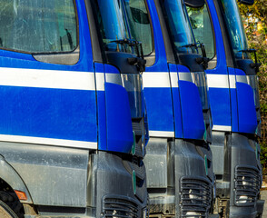 Three heavy truck car vehicles parked in a row on a parking. Blue trucks in the road. Lorry transport delivering freight cargo