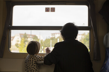 Grandparent and kid observing scenery, Child and grandparent engage with passing urban landscape...