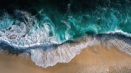 Aerial view of ocean waves crashing on a sandy beach shoreline.
