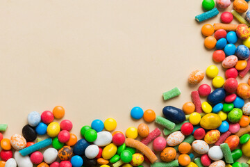 Fototapeta premium Mixed collection of colorful candy, on colored background. Flat lay, top view. frame of colorful chocolate coated candy