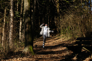 Fototapeta premium Female adventurer exploring sunlit forest trail in autumn