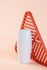 White cosmetic product or sunscreen cosmetic with stylish props on light orange background.