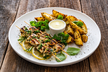 Greek style chicken skewers souvlaki with baked potatoes on wooden background

