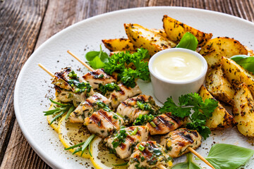 Greek style chicken skewers souvlaki with baked potatoes on wooden background

