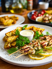 Greek style chicken skewers souvlaki with baked potatoes on wooden background

