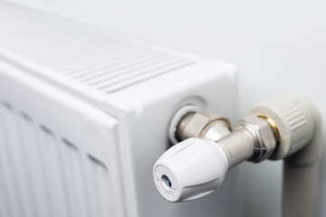 A steel panel heating radiator is placed under the windowsill on a white