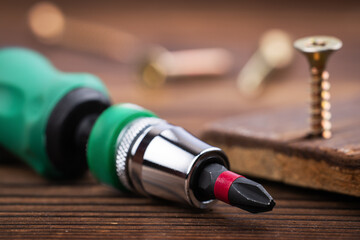 Screwdriver and screws on wooden background. Self-tapping screw. Screws macro photo.