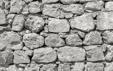 Cloud Dancer, trendy off-white color of the Year 2026. Rough stacked stone wall with irregular light