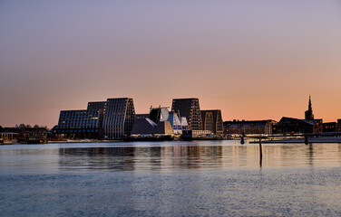 Papirøen or Papiroen sunset, new waterfront district in Copenhagen. Contemporary angular buildings mirrored in calm harbour water showcase cutting edge Nordic architecture and modern urban lifestyle
