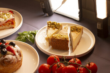 A delicious cheesecake topped with pistachios, alongside fruit pastries and juicy tomatoes for a colorful display