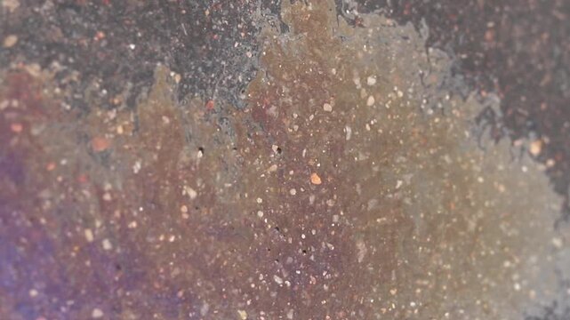 Gasoline spills create colorful patterns on water surfaces. The slick films float and reflect light, but they also harm the environment and release toxic chemicals