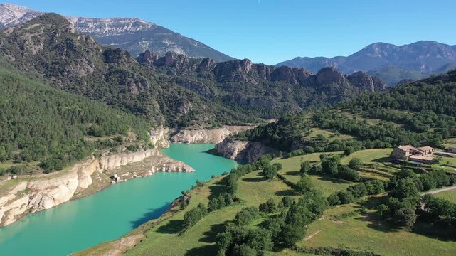 Turquoise Llosa del Cavall Reservoir on Cardener River winding through picturesque mountainous landscape in Catalonia, Spain, surrounded by lush greenery and rocky cliffs under clear blue sky