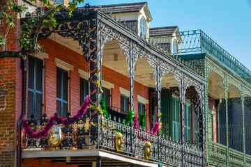 Balconies with intricate ironwork and Mardi Gras decor on a building in a street of the French...