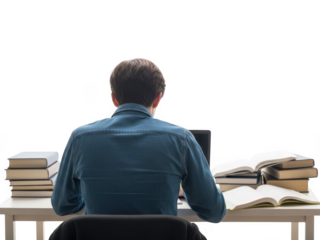 Young man focused on studying with books and laptop at desk.