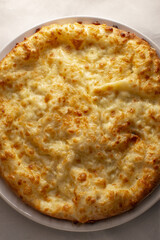 Delicious cheesy pizza, Rustic style pizza with gooey cheese on classic white dish, Overhead shot showcasing bubbling mozzarella and golden crust on simple