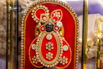 ornate deity dwarkadhish idol adorned with red velvet and sparkling stone embellishments
