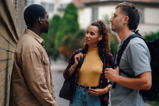 Three students talking on campus after class - Powered by Adobe